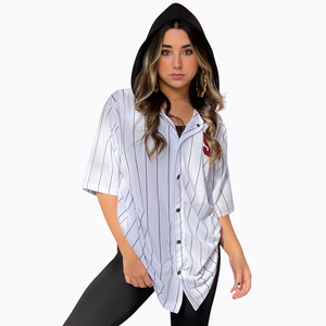 A woman modeling a white short-sleeve button-up baseball-style shirt with thin black pinstripes and a black hood attached to the collar, styled with black leggings against a plain white background.